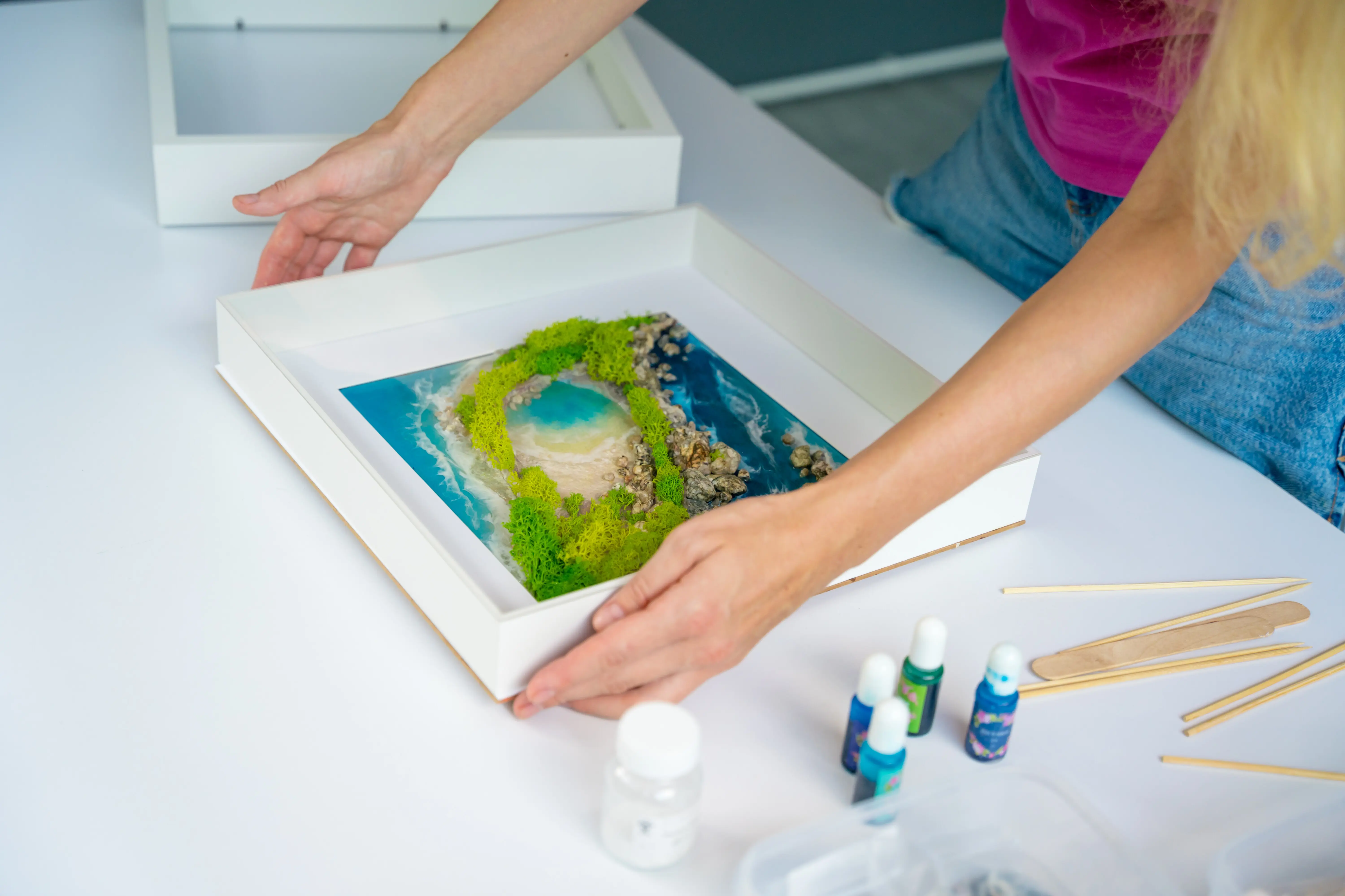 Der Prozess der Herstellung von Kunstdekor aus Epoxidharz, Natursteinen und Moos.