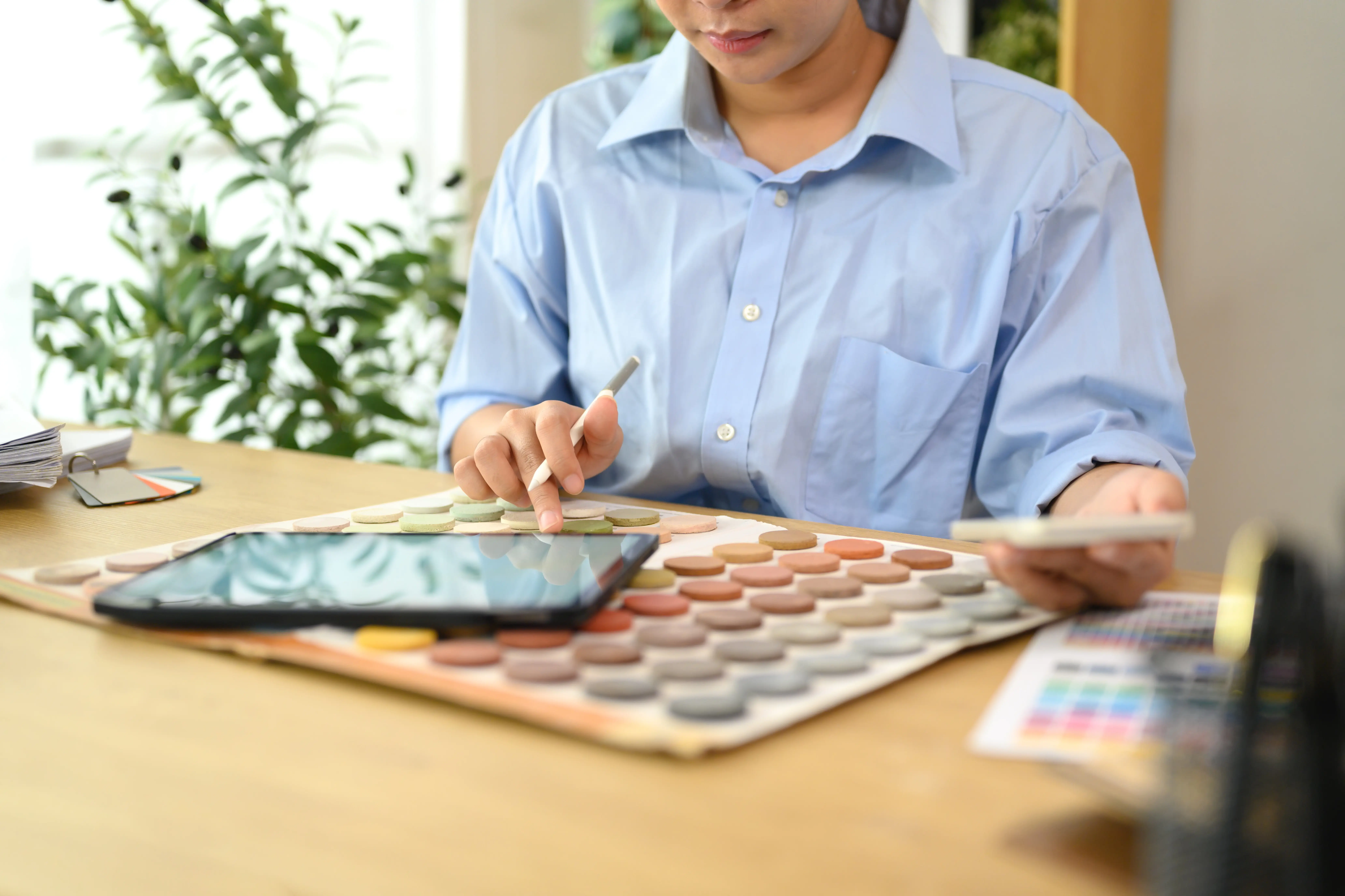 Innenarchitekt arbeitet am Schreibtisch und sichtet Farbmuster sowie Designmaterialien.